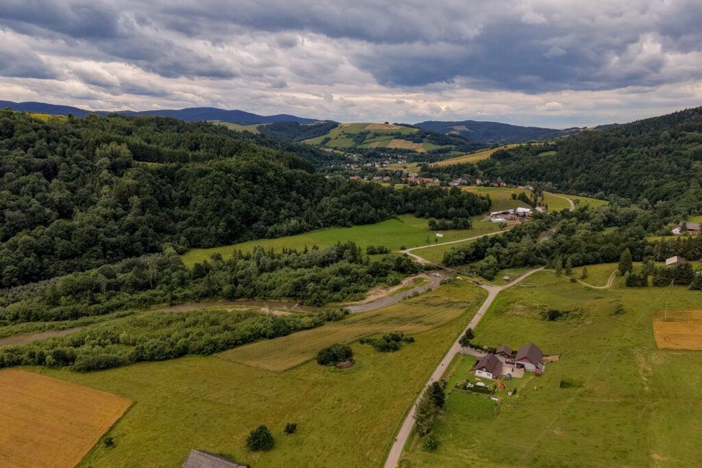Widok z drona na zieloną dolinę, pola, lasy i zabudowania