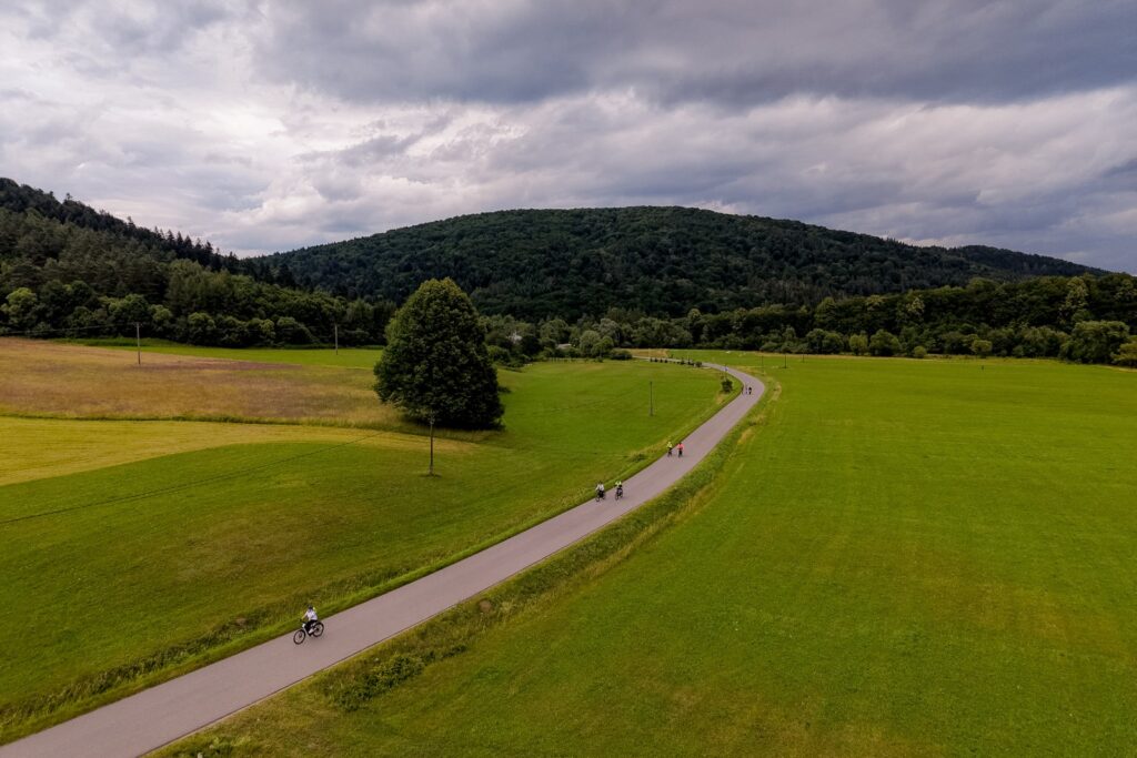 Widok z drona na uczestników rajdu jadących krętą drogą przez łąki