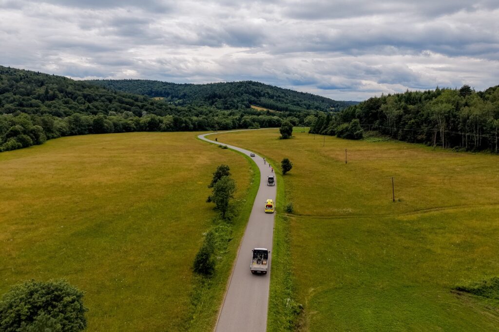 Widok z drona na uczestników rajdu jadących krętą drogą przez łąki