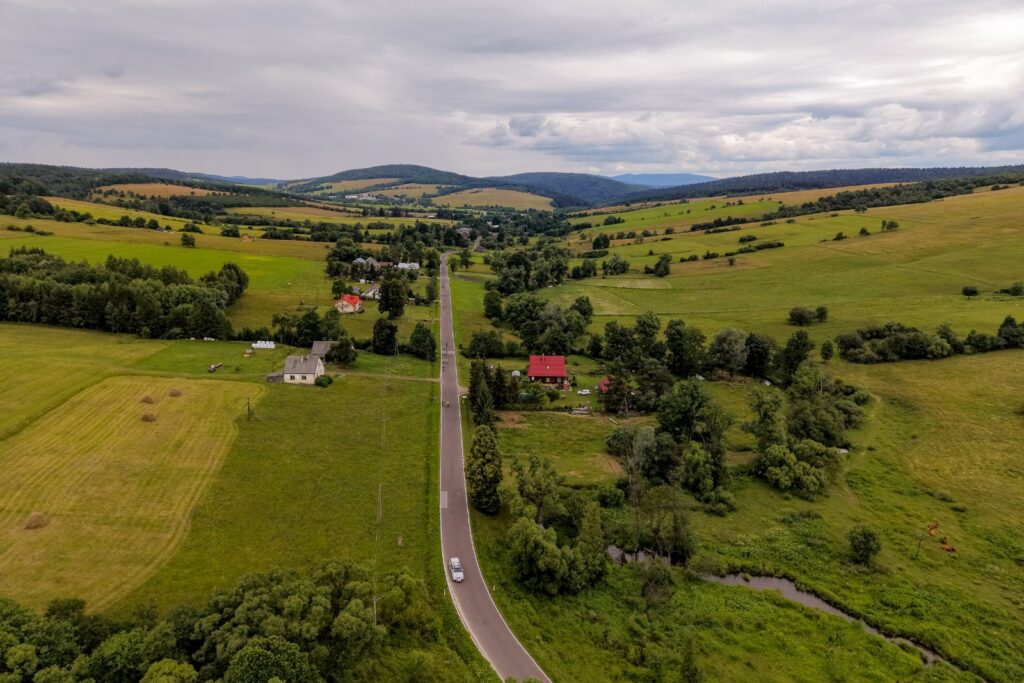 Widok z drona na krajobraz z drogą i jadącymi rowerzystami