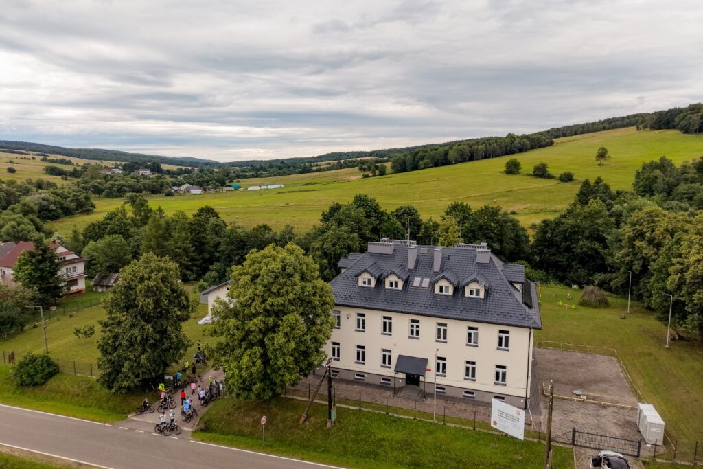 Widok z drona na budynek i uczestników rajdu na rowerach