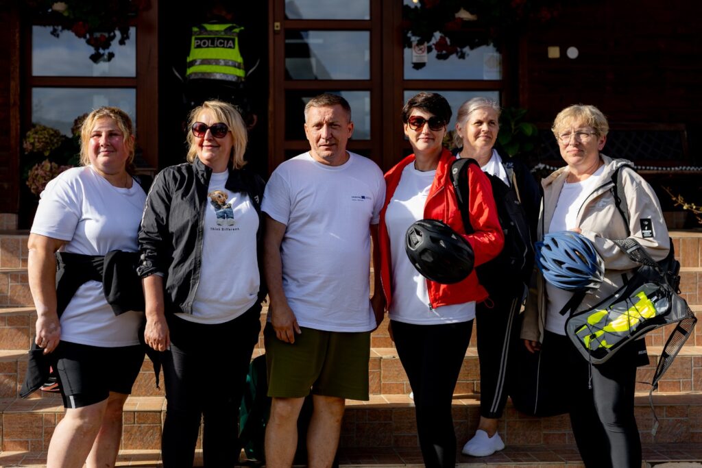 Sześcioro uczestników rajdu rowerowego pozuje do wspólnego zdjęcia przed budynkiem.