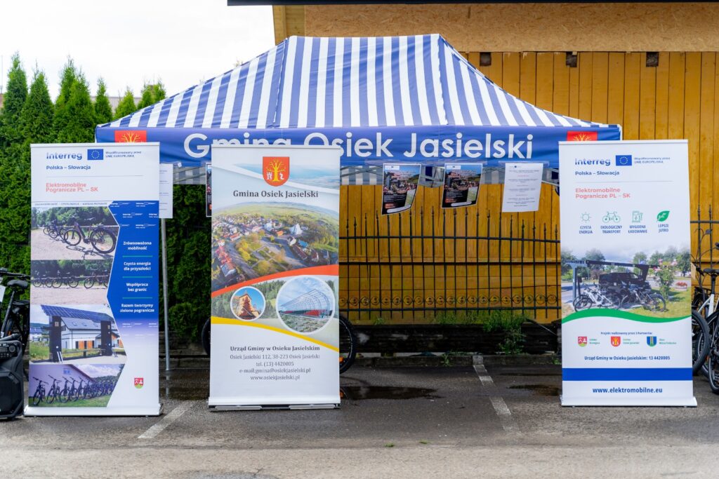 Namiot z napisem „Gmina Osiek Jasielski” i trzema rollupami reklamowymi projektu Elektromobilne Pogranicze PL-SK.