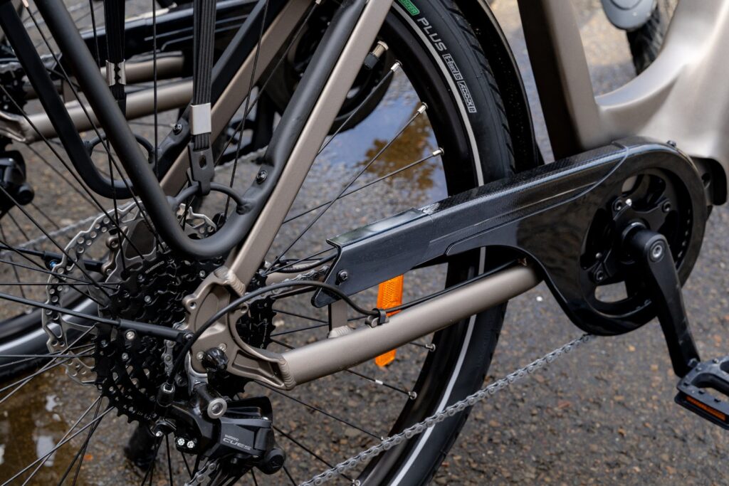 Zbliżenie napędu roweru elektrycznego z przerzutką Shimano Cues, łańcuchem i tylnym kołem.