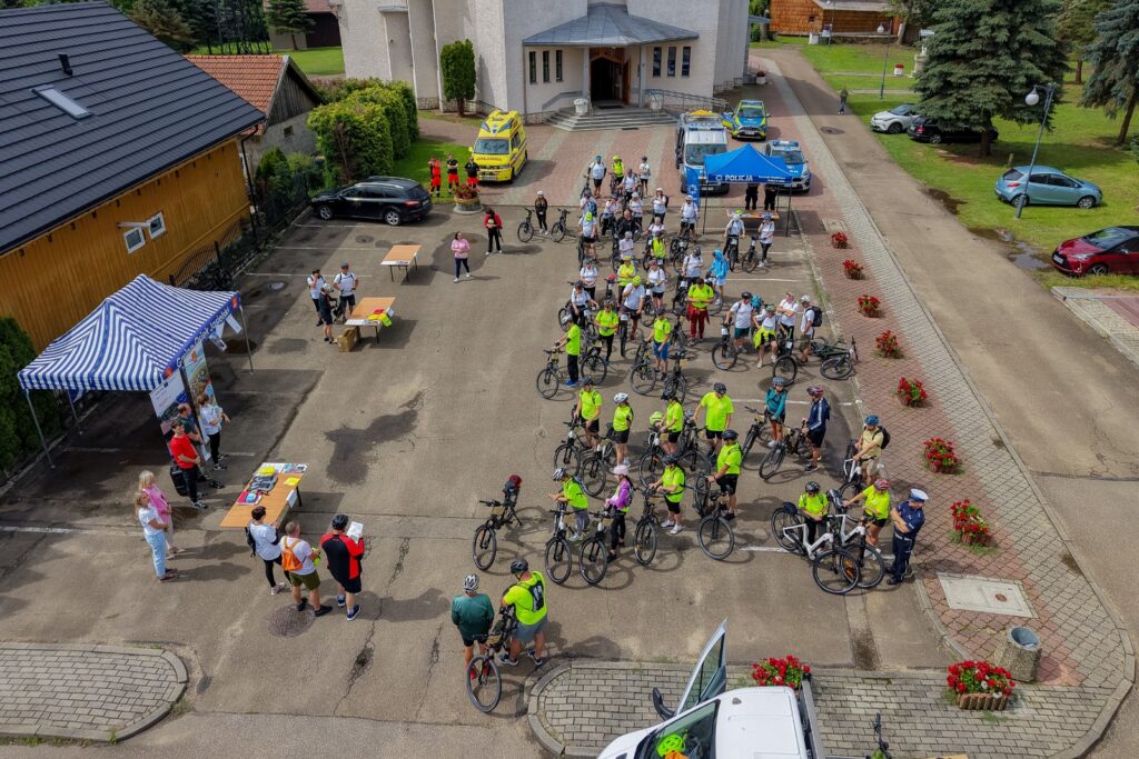 Widok z lotu ptaka na duży plac przed kościołem z liczną grupą rowerzystów oraz namiotem policyjnym.