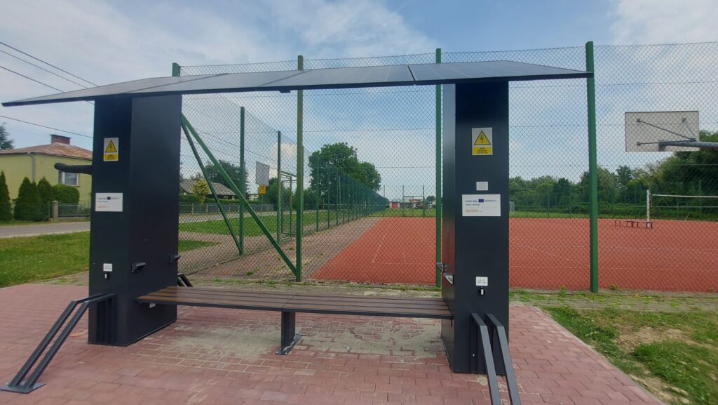Solarna stacja ładowania rowerów elektrycznych, w tle boisko w Załężu