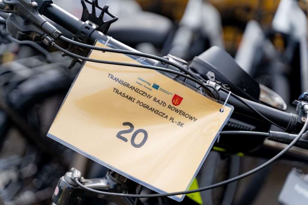 Tabliczka z numerem 20 i nazwą "Transgraniczny rajd rowerowy trasami pogranicza PL-SK" zamontowana na kierownict roweru