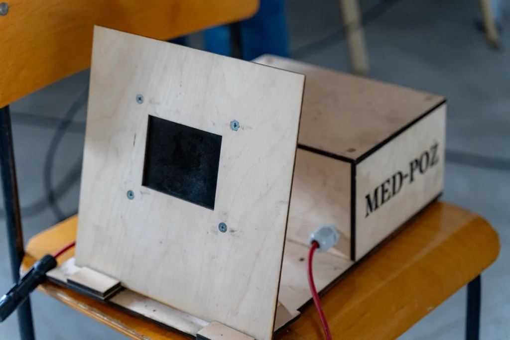 Wooden training box marked MED-POŻ with a red cable, a panel with a small window in front