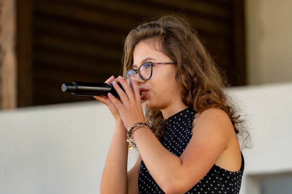 The youth band's vocalist, seen in profile, sings into a microphone held in both hands
