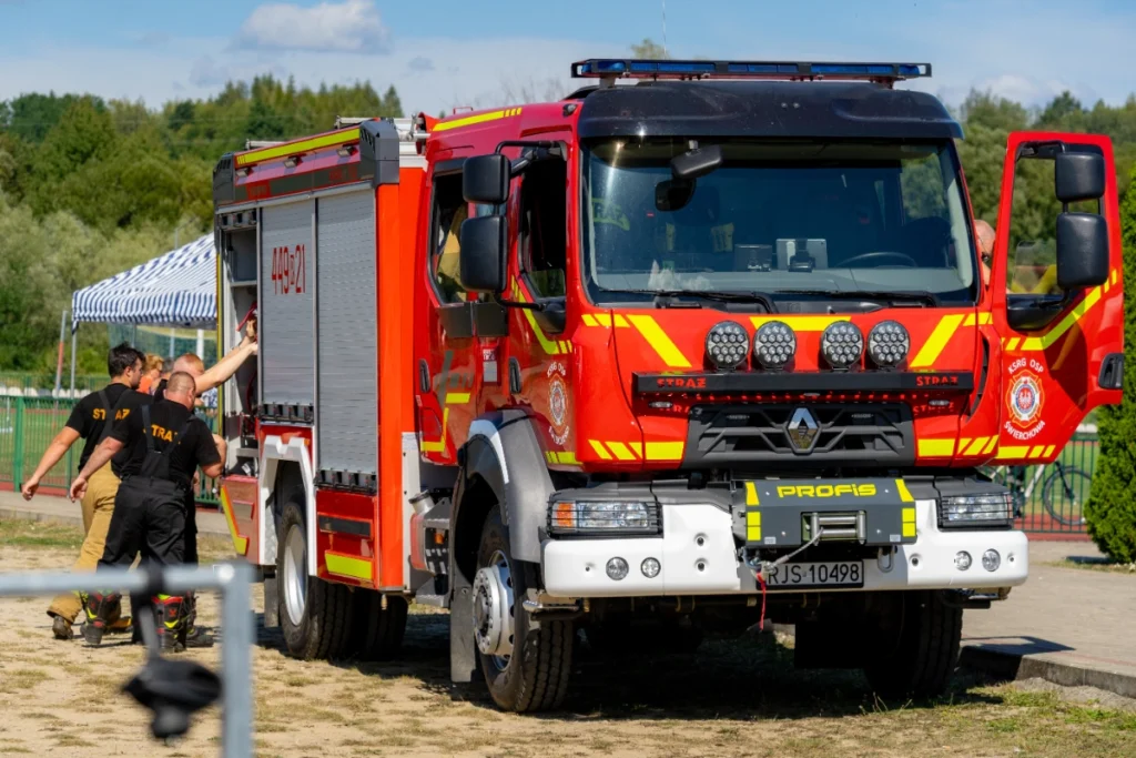 Świerchowa volunteer fire brigade's fire engine with open cab doors, volunteer firefighters by an open locker