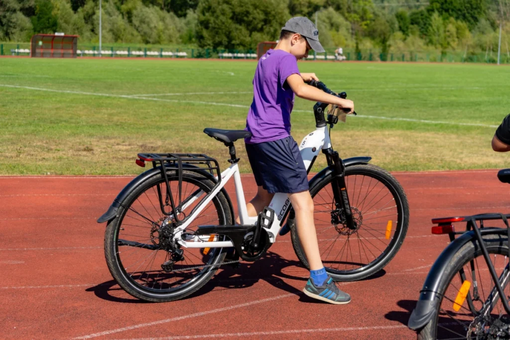 A boy gets ready to ride a white electric bike on the red stadium running track