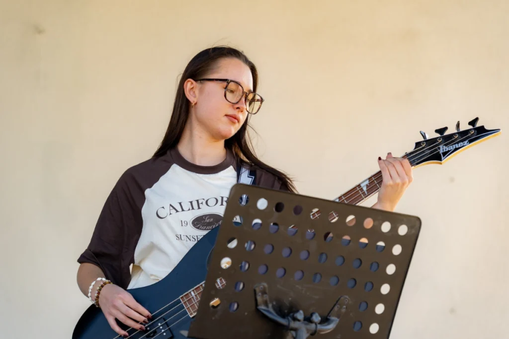 The band's bassist plays a navy bass guitar behind a black metal music stand
