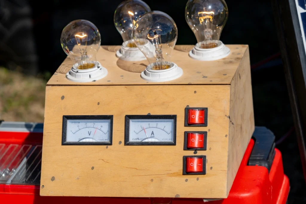 Wooden training box with four light bulbs, a voltmeter, an ammeter and three red switches