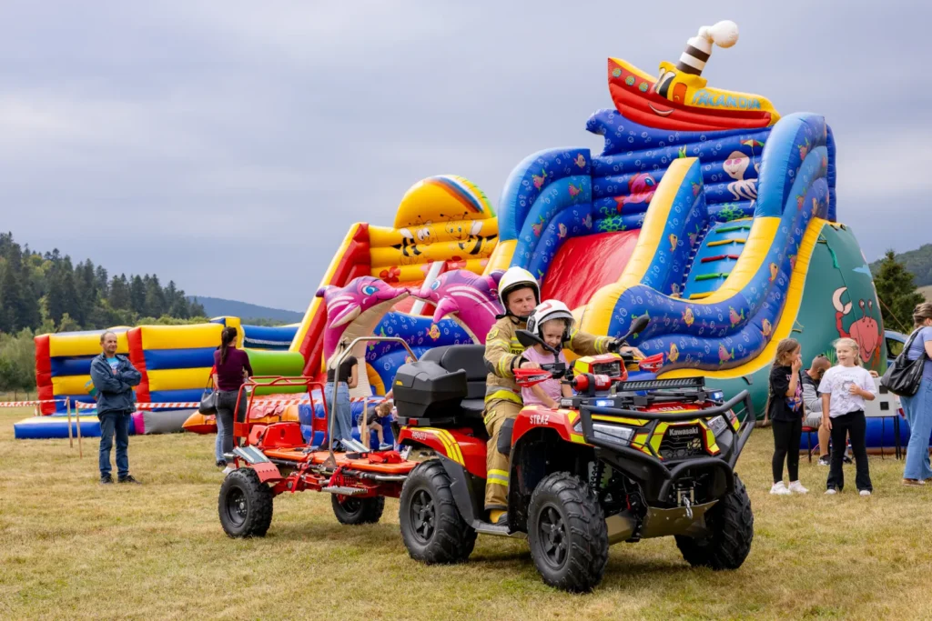 Quad strażacki z przyczepką i noszami na tle dmuchanego zamku ze zjeżdżalnią